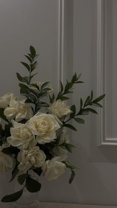 a vase filled with white flowers sitting on top of a counter next to a door