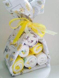 a stack of folded towels sitting on top of a white toilet paper holder with yellow ribbon