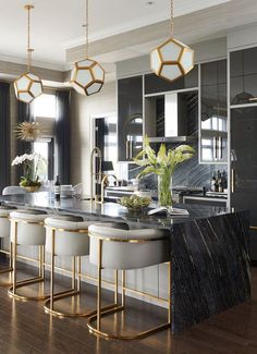 an elegant kitchen with marble counter tops and gold accents, along with bar stools