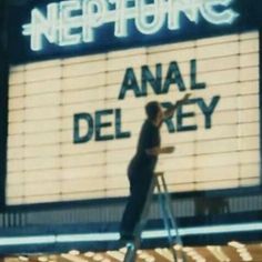 a man standing on top of a step ladder in front of a theater marquee