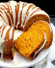 a bundt cake with white icing sitting on a plate next to a slice cut out