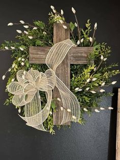 a cross hanging on the side of a wall next to a wreath with white flowers