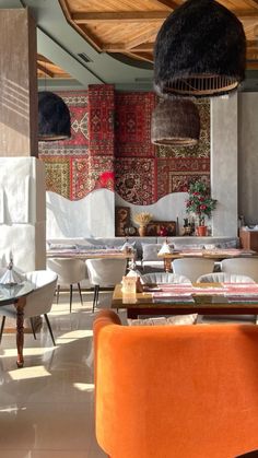 the interior of a restaurant with orange chairs and rugs hanging from the ceiling above