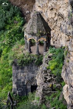 an aerial view of a stone structure on the side of a cliff with trees and bushes