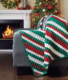 a christmas blanket is draped over a couch in front of a fireplace