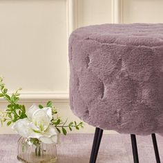 a small stool next to a vase with flowers