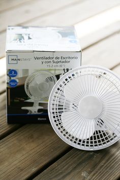 a small white fan sitting on top of a wooden table next to a cardboard box