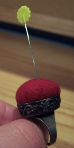 a tiny red hat sitting on top of a piece of metal with a needle sticking out of it