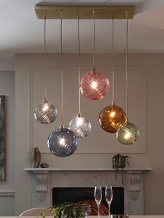 a dining room table with wine glasses hanging from it's ceiling and an open fire place in the background