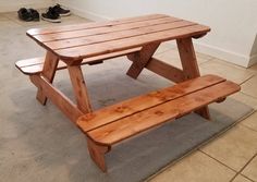 a wooden picnic table sitting on top of a carpeted floor next to a pair of shoes