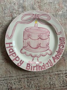 a pink birthday cake plate with the words happy birthday america on it and a lit candle