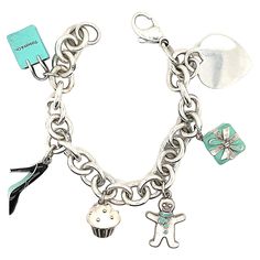 Charming charm bracelet. Made and signed by TIFFANY & CO. Sterling silver bracelet, with a sterling heart charm and five enamel figural charms: a Tiffany bag, a Tiffany box, a cupcake, a high-heeled shoe and a gingerbread man. . 7" long. A perfect gift for the sophisticated young woman in your life. Alice Kwartler has sold the finest antique gold and diamond jewelry and silver for over forty years. Elegant Bracelet Tiffany & Co., Tiffany Charm Bracelet Tiffany & Co., Sterling Silver Bracelets Women Tiffany & Co., Tiffney And Co Jewelry, Designer Enamel Jewelry As A Gift, Designer Enamel Jewelry For Gift, Silver Charm Bracelet With Logo For Gift, Silver Charm Bracelet With Logo As Gift, Tiffany Charm Bracelets