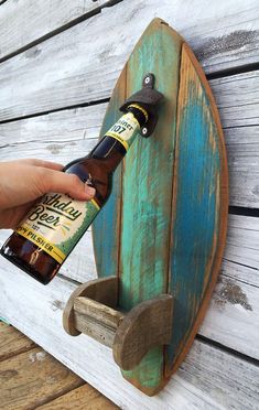 a person is holding a beer bottle in front of a surfboard