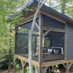 a small cabin in the woods with a screened porch