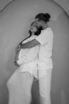 black and white photograph of a woman leaning against a wall with her arms around her body