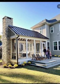 two people standing on the front porch of a house with an awning over it