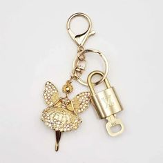 a gold keychain with a little fairy on it's side and a lock in the middle