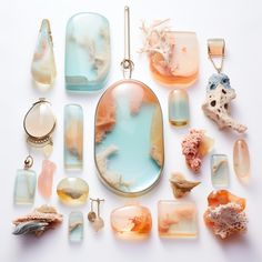 an assortment of sea glass and corals on a white surface with necklaces hanging from them