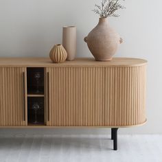 a wooden cabinet with two vases on top