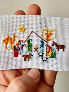 someone is holding up a small cross stitched christmas nativity scene with the birth of jesus