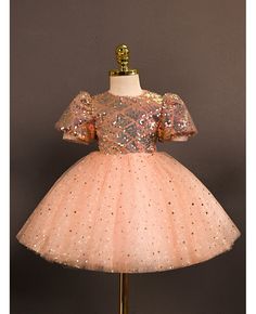 a pink dress with gold sequins on the top and bottom, sitting on a mannequin