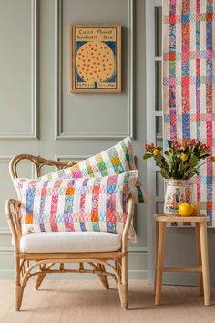 a chair and table with flowers in vases on the floor next to a wall