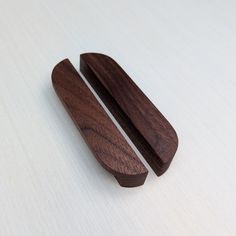 two pieces of wood sitting on top of a white table next to an object that looks like a pair of scissors