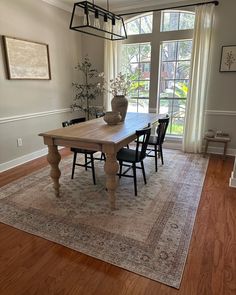 a dining room table with chairs and a rug on the floor