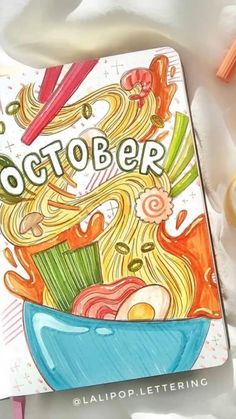 an open notebook with the words october written on it next to markers and pencils