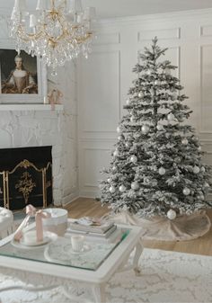 a living room decorated for christmas with a white tree in the corner and presents on the coffee table