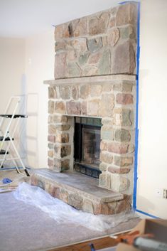 a stone fireplace being installed in a room with blue tape on the walls and floor