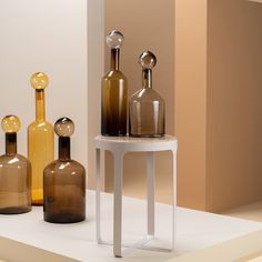 three glass bottles sitting on top of a white table next to each other in different shapes and sizes