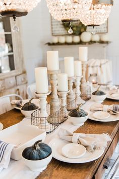 the table is set with white dishes and candles