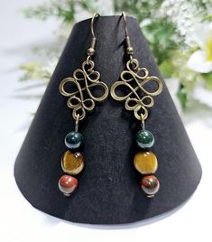 These beautiful handmade dangle drop earrings have been lovingly made to a high standard using Bronze tone earring hooks, connected to Antique Bronze tone metal alloy Filigree connectors. They are finished perfectly with genuine A grade 6mm Picasso Jasper, Tigers Eye & Indian Agate Gemstones  The earrings are approximately 5cm long from top ( where it leaves the ear ) to the bottom. They are about 2cm wide at the widest point. Jasper occurs in a kaleidoscope of colours. It's widely used for its Adjustable Beaded Earrings With Natural Stones, Adjustable Beaded Earrings With Natural Stones For Gift, Artisan Natural Stone Beaded Earrings As Gift, Handmade Agate Round Bead Earrings, Natural Stone Beaded Drop Earrings For Gifts, Spiritual Beaded Drop Earrings, Spiritual Beaded Drop Earrings For Gift, Wire Wrapped Agate Earrings For Gift, Wire Wrapped Agate Earrings As Gift