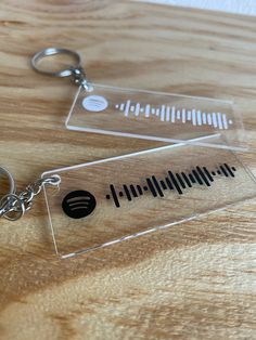 a pair of clear acrylic keychains sitting on top of a wooden table