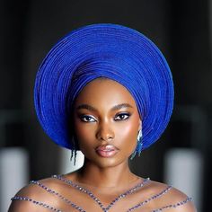 a woman with blue hair wearing a bright blue dress and large headdress is posing for the camera