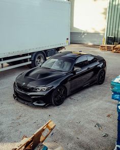 a black sports car parked in front of a truck