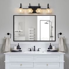 a bathroom vanity with two sinks and three lights on it's wall above the mirror