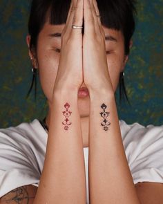 a woman covering her face with both hands while wearing matching tattoos on both arms and chest