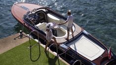 two people are standing on the deck of a boat in the water, while another person stands next to it