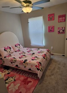 a bedroom with mickey mouse bedding and pink carpet