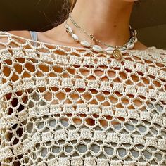 a woman wearing a white crochet top with pearls