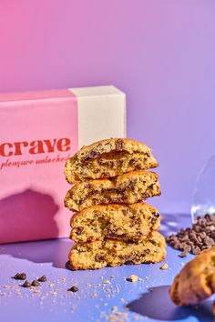 a stack of chocolate chip cookies next to a pink box