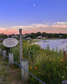 a sign is posted on the side of a fence next to a body of water