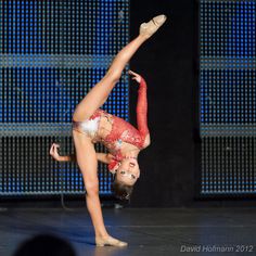 a young woman doing a handstand on stage