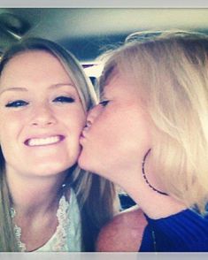 two beautiful women kissing each other in a car