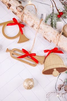 christmas decorations with bells and bows on a white tablecloth next to a tree branch