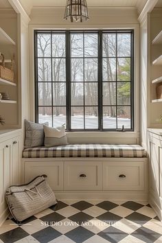 a window seat in the corner of a room with checkered flooring and white cabinets