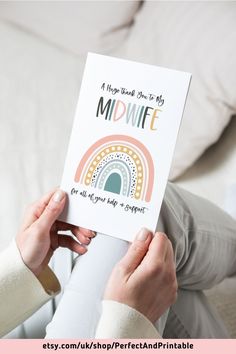 a woman holding up a card with the words midnife on it and an image of a rainbow