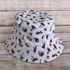 "Bucket Hat with colourful Fishing Flies on a Cream background.  Know a fisherman who need a lucky fishing hat? Great gift for a man who likes to fish. Soft flexible structure, easygoing aesthetic style made with a 100% Cotton fabric in a funky and colourful print allows the wearer to create their own individual fashion statement. One size - fits 21.5\" - 23\" head. Will be a loose fit on a 21.5\", tighter fit on 23\" 3 1/2\" Height from 2.25\" Interfaced Brim 100% Printed Quilting Quality Cotton fabric & 100% Cotton Solid Darker Beige Cotton Canvas fabric on reverse. Send Message for Custom Sizing Requirements! Fabric Note: These are handmade items, so pattern printed placement on fabric may vary depending on how it is cut. The fabric used in this item has been pre-washed to avoid shrinka Casual Summer Fishing Hat, Summer Fishing Bucket Hat With Short Brim, Adjustable Bucket Hat For Fishing, Spring Bucket Hat For Fishing, Spring Fishing Bucket Hat, Summer Fishing Bucket Hat With Brim, Brimmed Bucket Hat For Summer Fishing, Adjustable Bucket Hat For Fishing In Spring, Casual Bucket Hat For Fishing In Spring